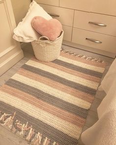 a basket with a heart on the floor next to a rug in a bathroom area