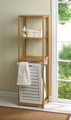 a wooden shelf with towels on it in front of a window and a white towel rack