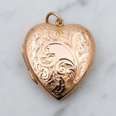 This sweet, heart shaped locket was made in England with a front and back cover of 9k gold and features a lovely engraved swirl vine design. This locket weighs 3.7 grams and measures 24mm tall not including the bail. The inner elements are most likely brass and it has the original photo frame and plastic cover on one side only. It is in great antique condition with light wear and is marked as shown.  **Available with a gold filled cable chain, choose from options above Heirloom Engraved Locket Necklace For Valentine's Day, Antique Heart Locket Necklace For Formal Occasions, Victorian Yellow Gold Heart Charm Locket Necklace, Victorian Yellow Gold Locket Necklace With Heart Charm, Victorian Engraved Heart Pendant Locket Necklace, Antique Yellow Gold Locket Necklace For Valentine's Day, Victorian Engraved Locket Necklace For Valentine's Day, 14k Gold Heart-shaped Engraved Locket Necklace, Engraved 14k Gold Heart Locket Necklace