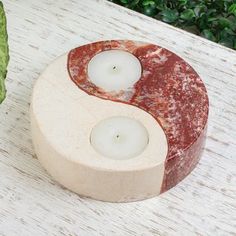 two candles in the shape of a yin - yang on a table with green leaves