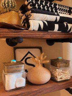 towels are stacked on top of a shelf next to other bathroom accessories and decor items