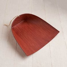 a wooden tray on a white surface with a string hanging from the top and bottom