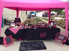 a pink and black tent set up for an outdoor event with chalkboard signs on it