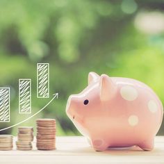 a piggy bank sitting on top of stacks of coins next to an upward graph