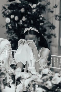 a woman sitting at a table in front of a christmas tree holding a napkin to her face