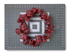 a red and black plaid wreath on top of a cutting board with the number nine