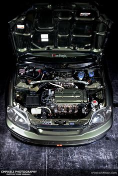 the engine compartment of a car with it's hood open and its lights on