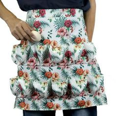 a woman wearing an apron with flowers on it and holding something in her hand,