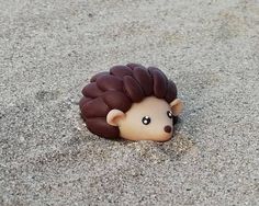 a small toy hedgehog laying in the sand