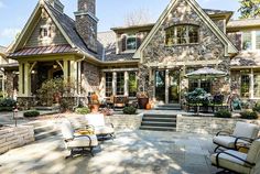 an outdoor patio with chairs and tables in front of a house