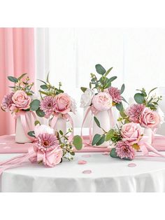 pink flowers and greenery in vases on a table