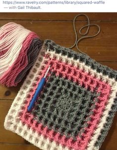 a crocheted square with yarn and a ball of thread on the floor next to it