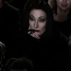 a woman with black hair and blue eyes is sitting in the audience at a fashion show