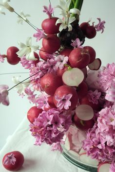 a vase filled with lots of flowers and radishes on top of a table