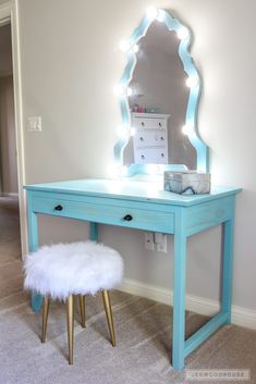 a blue vanity table with a mirror and stool in front of it on carpeted floor