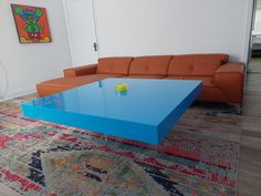 a blue coffee table sitting on top of a rug in front of a brown couch