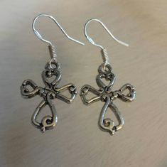 the earrings are made out of metal and have an intricate cross design on each side