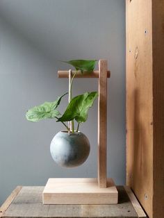 a potted plant in a wooden frame on top of a wood table next to a gray wall