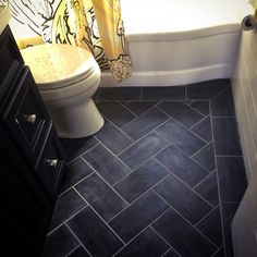 a white toilet sitting next to a bath tub in a bathroom under a yellow shower curtain