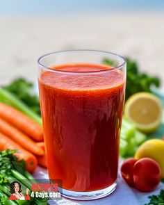 carrots, celery, and other vegetables on a table with a glass of juice