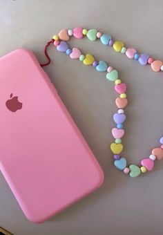 a pink phone case sitting on top of a table next to a beaded necklace