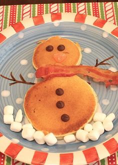 two pancakes with bacon on top and marshmallows in the shape of snowmen