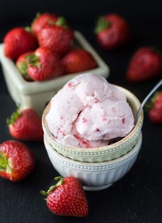 two bowls filled with ice cream and strawberries next to each other on a black surface