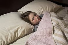 a young boy is sleeping in bed with his head tucked under the covers and pillows