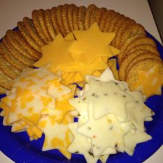 a blue plate topped with crackers and cheese next to star shaped crackers on a white counter