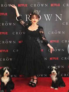 a woman standing next to two small dogs on a red carpet