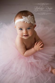 a baby girl wearing a pink tutu and headband