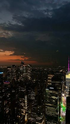 the city skyline is lit up at night, with skyscrapers in the foreground