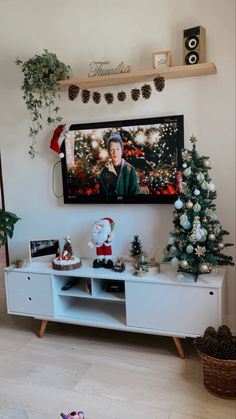 a flat screen tv sitting on top of a white entertainment center next to a christmas tree