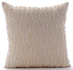 a beige pillow with white threadwork on the front and back, sitting on top of a