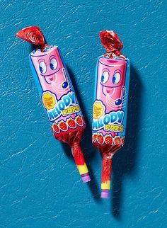 two candy lollipops sitting on top of a blue surface next to each other