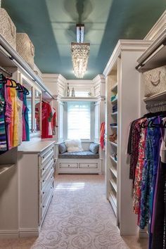 a walk in closet with lots of clothes hanging on the walls and drawers, along with a window seat