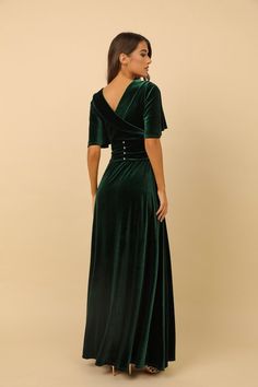 a woman wearing a green velvet dress with an open back and buttons on the side