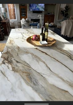 a marble counter top with wine bottles and an apple on the plate next to it