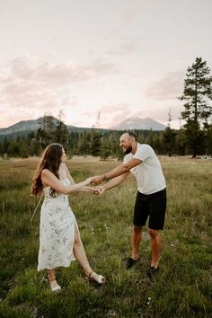 a man and woman holding hands in the grass