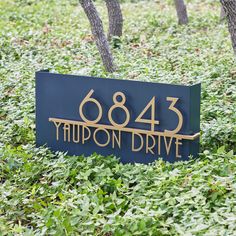 a blue sign sitting in the middle of a lush green field next to some trees