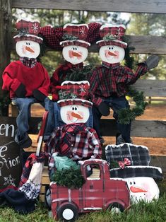 a group of snowmen sitting on top of a wooden bench next to christmas decorations