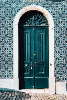 a green door in front of a blue and white wall with an arch above it