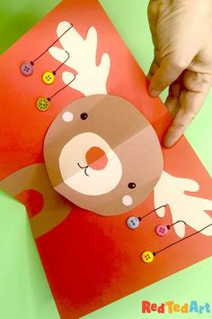 someone is making a reindeer card out of construction paper and buttoning it with scissors