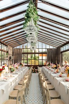 an indoor dining area with tables, chairs and chandelier hanging from the ceiling