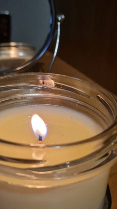 a lit candle sitting in front of a mirror