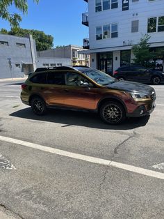 a brown and black car parked on the side of the road in front of a building