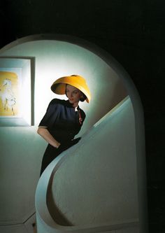 a woman in a yellow hat is standing on the stairs with her hands on her hips