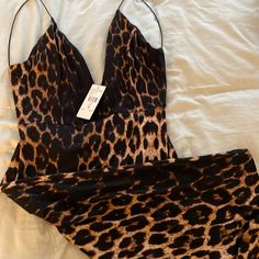 two pieces of clothing laying on top of a white bed covered in animal print fabric