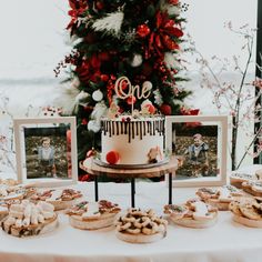 a table topped with cakes and cookies next to a christmas tree