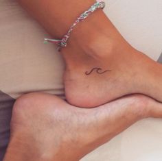 a woman's foot with a small wave tattoo on it